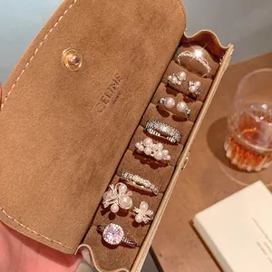 Collection of silver-tone French Baroque pearl rings inside a luxury suede jewelry box.