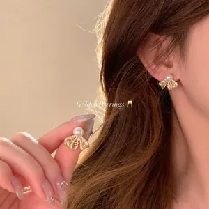 Elegante goldene S925 Sterlingsilber Schleifenohrringe mit Perle in der Detailansicht am Ohr