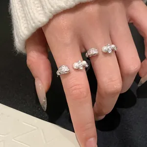 Detailaufnahme eleganter silberner offener Ringe mit Perlen und funkelnden Kristallen