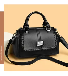 Detailed view of black pebbled leather handbag with braided trim and metal logo plaque