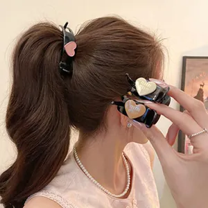 Vista detallada de pinzas para el cabello en forma de corazón con letras de marca