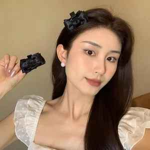 Vista detallada de una dulce pinza para el pelo con lazo negro usada por una modelo