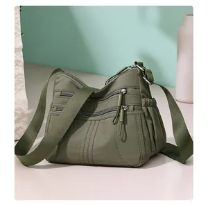 Detailed close-up view of a green multi-pocket crossbody bag featuring smooth zipper details