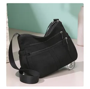 Detailed view of black multi-pocket nylon crossbody bag with smooth metallic zippers