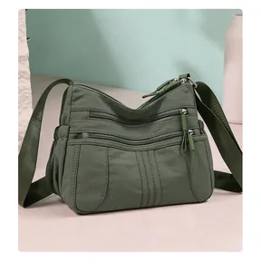 Close-up of a dark green multi-pocket nylon crossbody bag in a minimalist scene