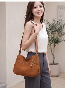 Stylish brown nylon crossbody bag with multiple zippers, worn by a female model