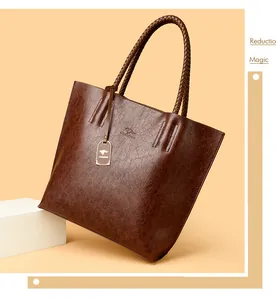 Primer plano de un bolso tote de cuero marrón vintage con asas trenzadas y logo