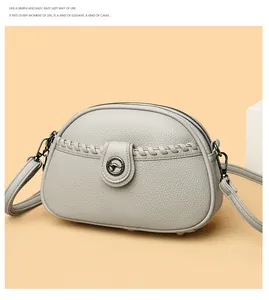 Macro view of grey pebbled leather crossbody bag featuring a circular kangaroo logo