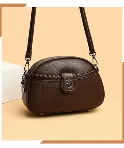 Close-up of a brown soft leather crossbody bag featuring multiple zip compartments