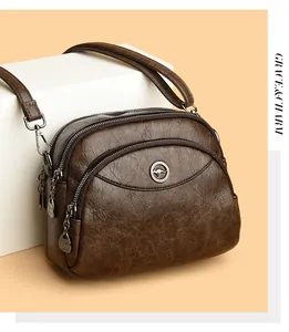 Detail view of brown textured leather crossbody bag with three zip compartments for women