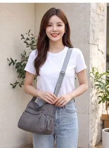 Stylish grey multi-pocket crossbody bag in soft leather worn by a female model outdoors