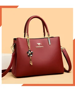 Elegant red textured leather handbag with gold kangaroo logo and floral charm detail.