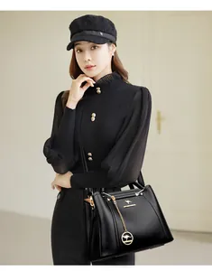 Detalle de elegante bolso de mano negro de gran capacidad en cuero con dije en la modelo