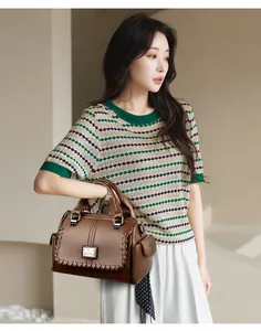 Elegant Asian model holding a classic brown handbag with textured finish and woven edge details