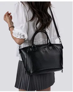 Detailed view of a large black leather handbag worn by a model for casual style