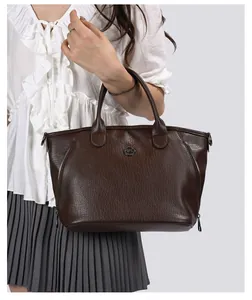 Detailed view of vintage large brown leather tote bag carried on a model's shoulder.