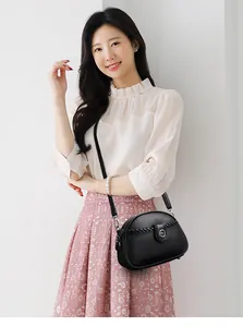 Elegant black soft leather crossbody bag with braided detail worn by an Asian model