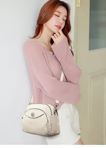 Close-up detail of a cream white three-layer crossbody bag worn by an Asian model