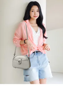 Chic grey soft leather crossbody bag worn by a model in a casual summer outfit