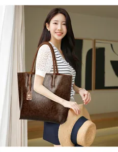 Bolso tote de gran capacidad en cuero marrón texturizado llevado por una modelo.