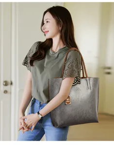 Detalle de un elegante bolso tote gris de cuero con asas trenzadas en una modelo