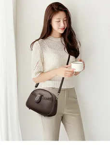 Close-up view of a dark brown soft leather crossbody bag with kangaroo logo worn by model