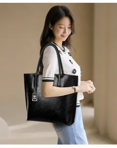 Elegante modelo asiática llevando un gran bolso tote de cuero negro texturizado de moda