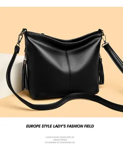 Detailed view of black pebbled leather shoulder bag with decorative tassels