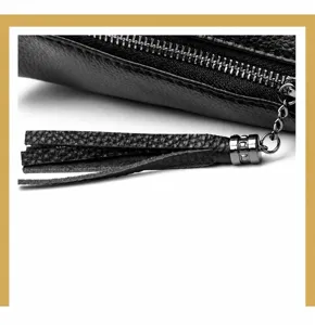 Close-up detail of black litchi grain leather bag with stylish tassel and zipper