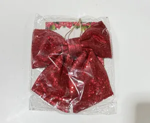 Detailweergave van een grote rode kerststrik met lovertjes in de plastic verpakking