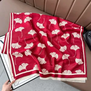 Dettaglio di uno scialle rosso tipo cashmere con motivi di foglie di ginkgo bianche.