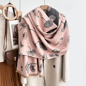 Elegante sciarpa rosa con stampa di foglie di ginkgo su un cappotto beige, vista di dettaglio