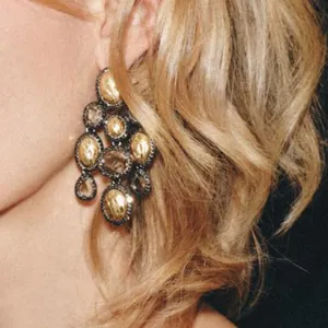 Close-up of retro ethnic style resin chandelier earrings in gold and black on a model.