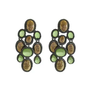 Detailed macro view of vintage drop earrings featuring green resin and hammered gold