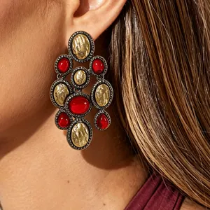 Vintage bohemian statement earrings with red resin and gold textured accents.