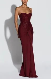 Elegant burgundy strapless evening gown featuring a sequin bodice and draped maxi skirt