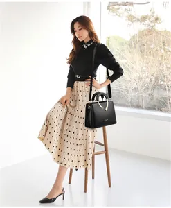 Elegante schwarze Handtasche mit Lychee-Muster, kombiniert mit einem Midirock-Outfit
