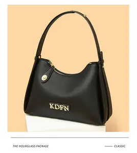 Detailed macro view of classic black pebbled leather shoulder bag with gold metal logo