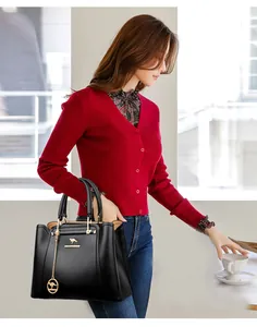 Una modelo presentando un elegante bolso de cuero negro con detalles dorados.