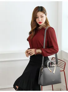 Elegante graue Handtasche mit Narbenleder-Optik, präsentiert von einem Model im Studio