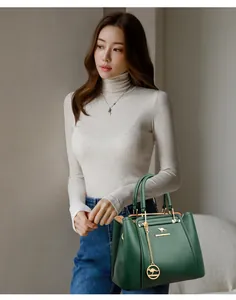 Detalle de un bolso de mano de cuero verde oscuro sostenido con estilo por una modelo