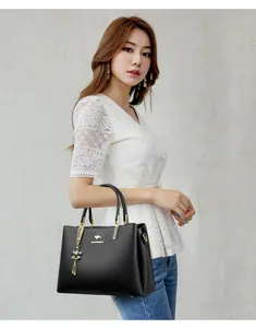 Elegant Asian model holding a black leather handbag with kangaroo logo and gold accents