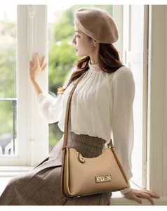 Elegant beige KDPE crossbody bag shown in a lifestyle setting with a beret and blouse