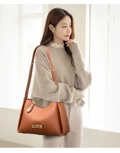 Elegant brown textured leather shoulder bag showcased by a female model indoors