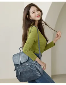 Femme portant un grand sac à dos vintage en cuir souple bleu dans un cadre moderne