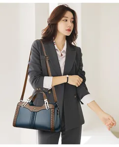 Modella professionista che presenta una borsa a tracolla in pelle blu con finiture marroni.