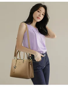 Elegant tan leather handbag for women featuring a stylish shoulder strap and charm.