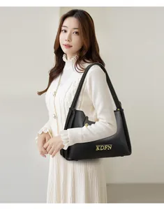 Detail view showing black pebble leather texture and gold logo on the shoulder bag