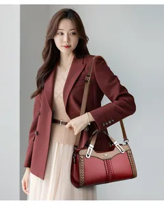 Borsa a mano in pelle bordeaux con dettagli intrecciati indossata da una modella.