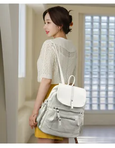 Vue latérale d'un sac à dos élégant en cuir souple blanc pour femme porté par un modèle